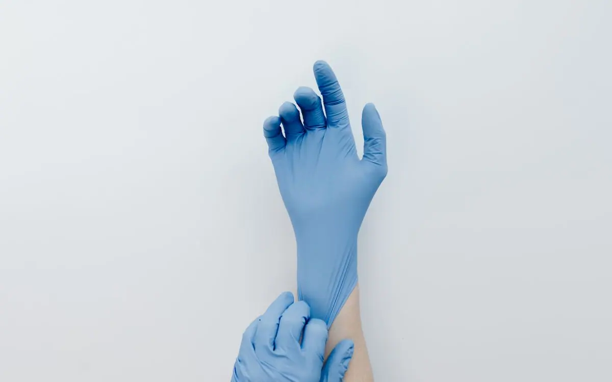 Mains enfilant des gants de nitrile bleus